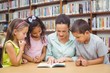 © WavebreakMediaMicro - Pupils and teacher reading book in library