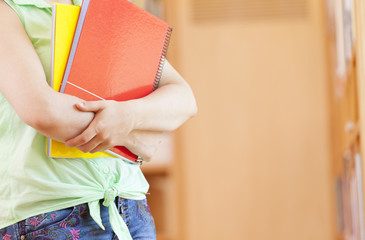 Cropped image of a female student holding notebooks at the libra