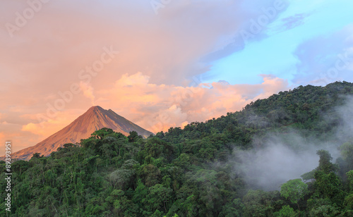 Plakat Zachód słońca przez wulkan Arenal w Kostaryce, chmury chmur lasu wznoszą się od podłogi dżungli