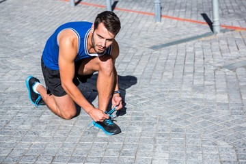 Poster - Handsome athlete tying his shoes on a sunny day