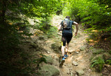 Fototapeta Góry - trail runner with backpack running up the steep hill