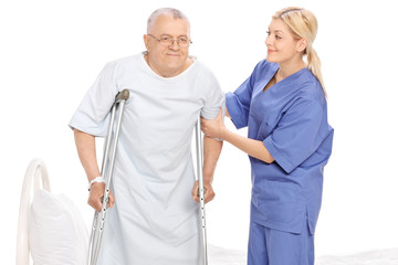 Poster - Young female nurse helping a senior patient with crutches