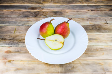 Two and half pears in white plate, rustic wooden table