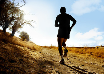 Silhouette sport man running on countryside in cross country at summer sunset