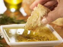Hand Dipping A Piece Of Bread Into Olive Oil