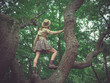 Woman wearing safari hat climbing tree