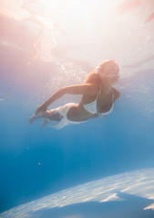 Wall Mural - Young woman swimming underwater