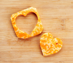 Poster - Cheese slice with cut in shape of heart on wooden background