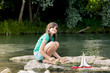 © Westend61 - Girl playing with wooden toy boat at a river