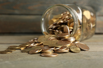 Poster - Glass jar with coins on wooden background