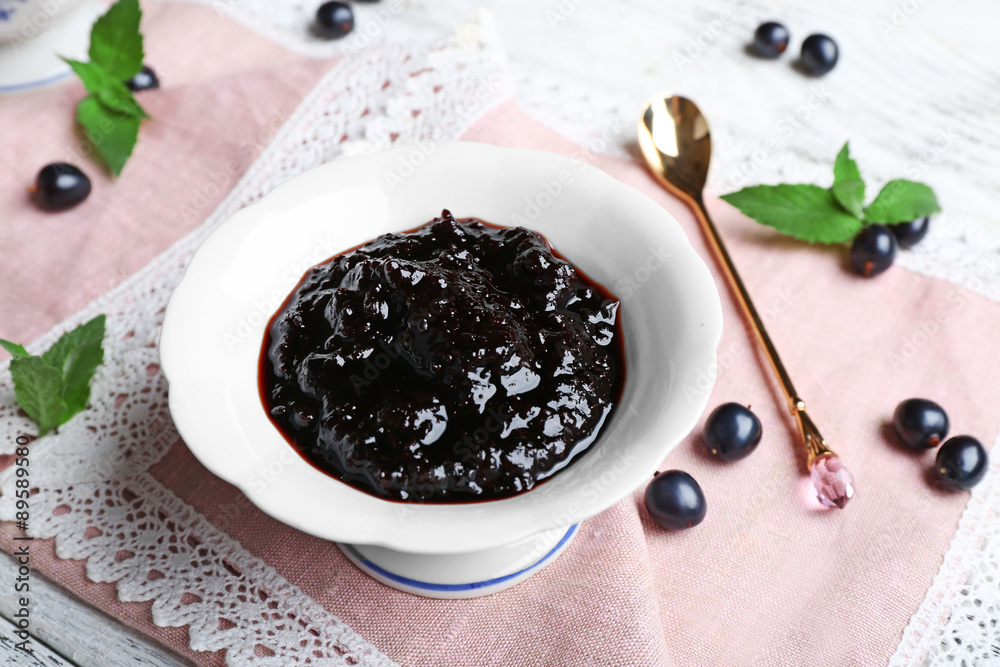Tasty currant jam with berries on table close up