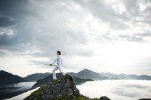 Austria, Kranzhorn, Mid Adult Woman Exercising Stick Fighting On Mountain Top