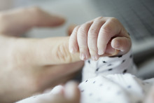 Close-up Of Baby Holding Father's Finger
