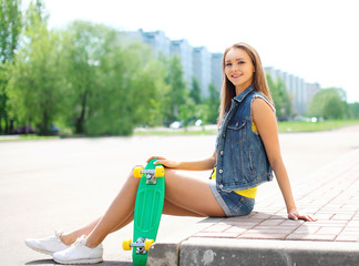 Wall Mural - Fashion pretty girl with skateboard having fun outdoors in the c