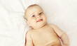 © rohappy - Portrait of smiling baby lying on the bed at home, top view