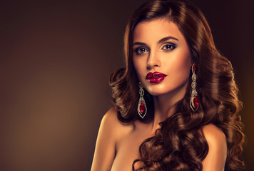 Beautiful model brunette with long curled hair  with large shiny earrings

