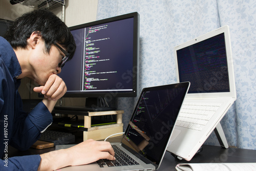 Fotografie, Obraz Stressed Asian engineer writing a programme on a computer