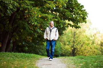 Happy senior man walking and relaxing in park