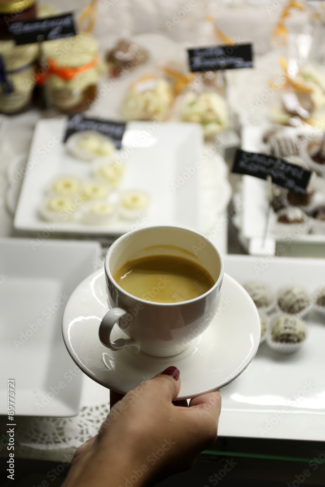 Female hand holding cup of coffee on table background