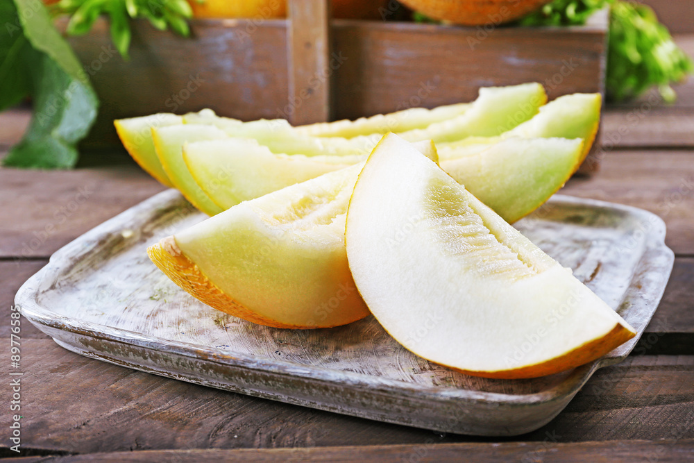 Ripe melons with green leaves on table close up