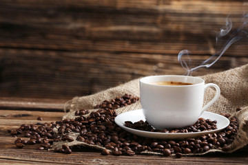 Poster - Cup of coffee with coffee beans on a brown wooden background