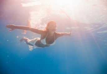 Wall Mural - Young woman swimming underwater