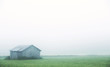 An old barn in the field on a very foggy morning. Image taken during sunrise in Finland. Image has a vintage effect applied.
