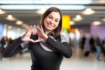 Young pretty girl make a heart with her hands over white backgro