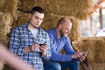 Wall Mural - Two farmers with phones at hayloft