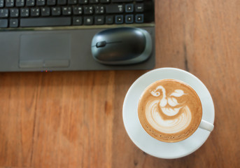 Wall Mural - Cafe latte with latte art on working desk soft focus background