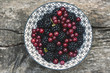 bowl with wild backberries and redcurrants on a hardwood table