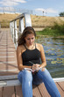 © Trepalio - Adolescente de 15 años escribiendo en el embarcadero. Chica rubia adolescente escribiendo en su diario junto al rio.