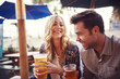 © Joshua Resnick - happy couple having a good time drinking beer together at outdoor pub or bar
