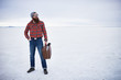 © Joshua Resnick - totally unconcerned lone traveling hipster standing with retro suitcase in vast empty salt flats
