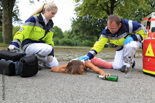 Fotografia, Obraz Junge Frau betrunken am Boden mit Sanitäter