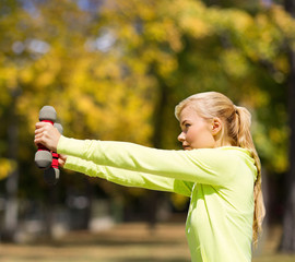 Wall Mural - sporty woman with light dumbbells outdoors