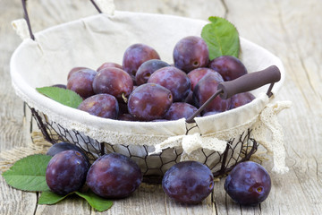 Wall Mural - fresh plums in a basket on wooden background