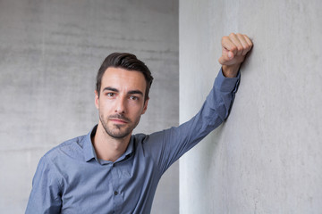 young man leaning at concrete wall