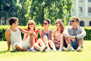 Canvas Print - group of smiling friends outdoors sitting on grass