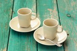 Fototapeta Mapy - Two empty ebony espresso cups with silver spoon on turquoise sha
