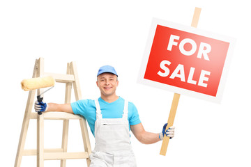 Wall Mural - Young male painter posing next to a wooden ladder and holding a