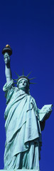 Wall Mural - This is a vertical shot of the Statue of Liberty against a blue sky.