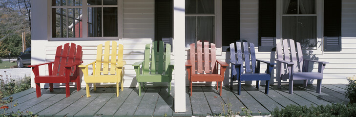 Wall Mural - This is the Salt Ash Inn Bed and Breakfast. it is a large white house with a large front porch. This is a close up of the front porch with brightly colored wooden chairs in front of the windows. The windows have blacks shutters on them.