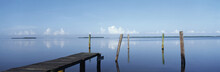 This Is The Morning View Of Pine Island Sound. Its Pier Juts Out From The Left Side With Wooden Pylons Standing Up Out Of The Water Near The Shore.