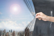 Woman hand pulling sunny sky cityscapes curtain covering stormy