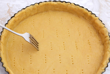 Fork making holes in a raw pastry case