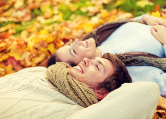 Canvas Print - close up of smiling couple lying in autumn park