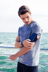 Sticker - Male runner listening to music adjusting settings on armband for smartphone