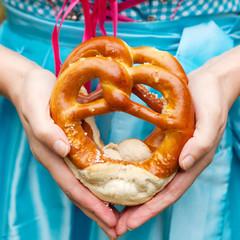 Wall Mural - Happy beautiful woman in dirndl dress holding Oktoberfest  pretz