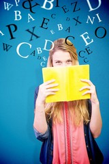 Canvas Print - Composite image of student covering face with book in library 